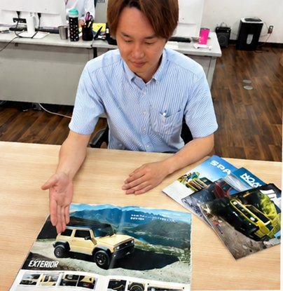 カタログを広げてお客様に車種を説明するスタッフ