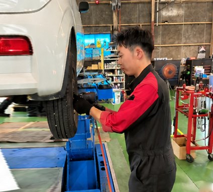リフトに上げた車両の足まわりを整備するスタッフ